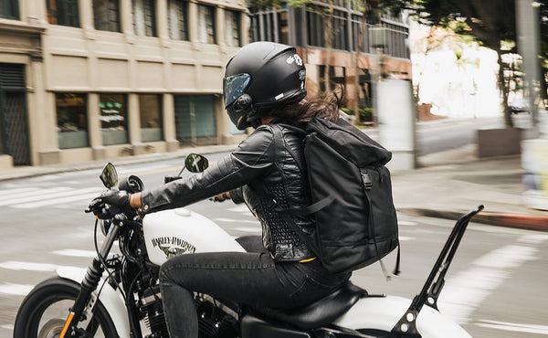 Woman wearing the Shadow Guide 33 while riding her Harley Davidson motorcycle in a downtown city area.